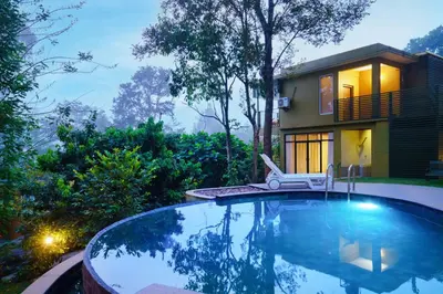 a swimming pool in front of a house at Kuruva Island Resort And Spa - By KABINI BREEZE in Mananthavady