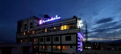 a hotel building with a neon sign on it at night at Hotel Nahar Manchester Inn in Coimbatore