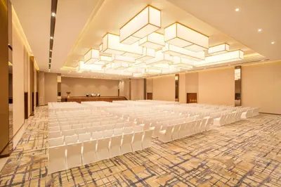an empty banquet hall with white chairs and a large chandelier at Hyatt Regency Thrissur in Trichūr