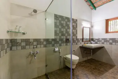 a bathroom with a shower and a toilet and a sink at amã Stays & Trails, Rare Earth Estate in Madikeri