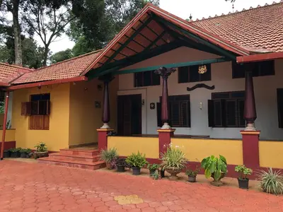 a yellow and white house with a red roof at amã Stays & Trails, Rare Earth Estate in Madikeri