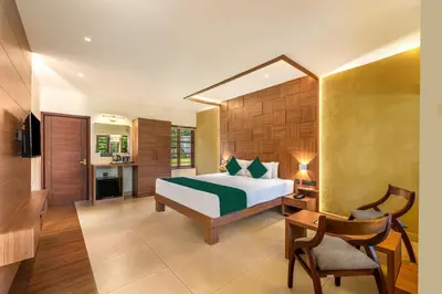 a bedroom with a bed and a desk and a chair at Sterling Govardhana Malampuzha in Palakkad
