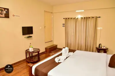 a hotel room with a bed and a television at mangosteen holidays in Vythiri
