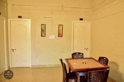 a room with a table and chairs and two white doors at mangosteen holidays in Vythiri