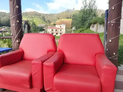 a pair of red chairs sitting on a porch at A Ooty Honey Huts in Ooty