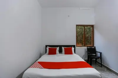 a bedroom with a bed with red pillows and a window at Hotel O Al Ameen Residency in Kannur
