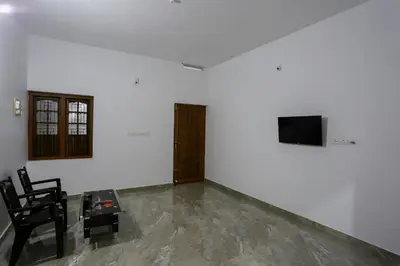 a living room with a table and a tv on a wall at Hotel O Al Ameen Residency in Kannur