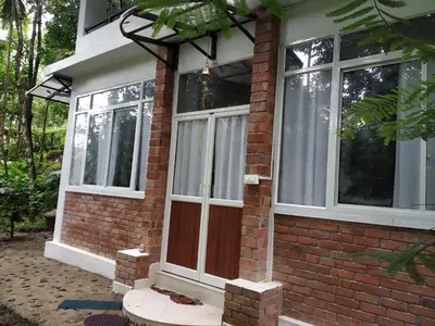 a brick house with a door and windows at Aruvi homestay in Vythiri