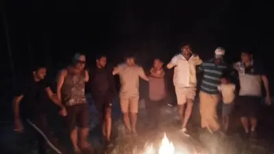 a group of people standing around a fire in the dark at Chamayam Holiday Villa in Meenangadi