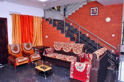 a living room with chairs and a staircase at Chamayam Holiday Villa in Meenangadi
