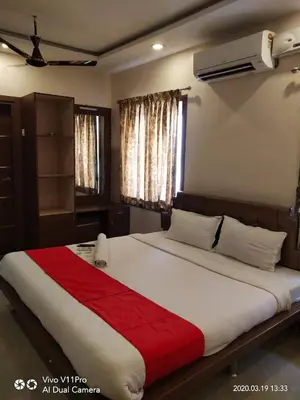 a bedroom with a large bed with a red blanket at Sri Kamadhenu Residency in Coimbatore