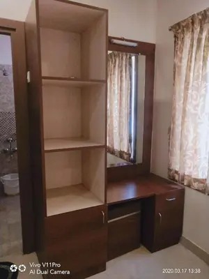 a large wooden cabinet with a mirror in a room at Sri Kamadhenu Residency in Coimbatore