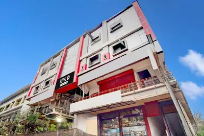 a tall white building with red doors and windows at Super Hotel O Kunnamangalam Near Bus Stand in Calicut