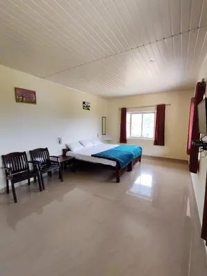 a bedroom with a large bed and two chairs at Aden Valley in Kanthalloor
