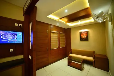 a hallway with a tv and a bench in a room at Hotel Priya in Kottakkal