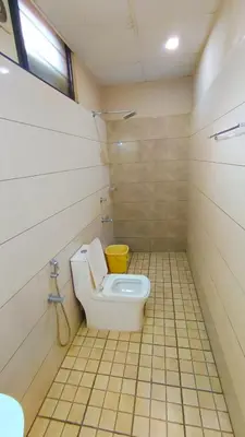 a bathroom with a toilet and a yellow bucket at Hotel Priya in Kottakkal