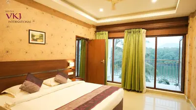 a bedroom with a bed and a large window at Hotel VKJ International Kuttampuzha in Thattakād