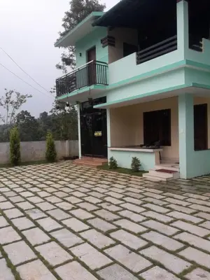 a house with a stone courtyard in front of it at Wayanad Snow Vibes in Vythiri