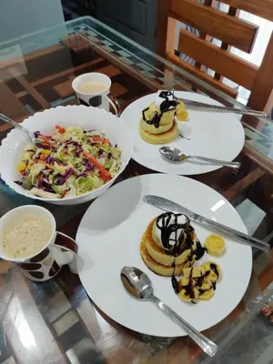 a glass table with plates of food on it at Villa Tesori Homestay Wayanad in Meppādi