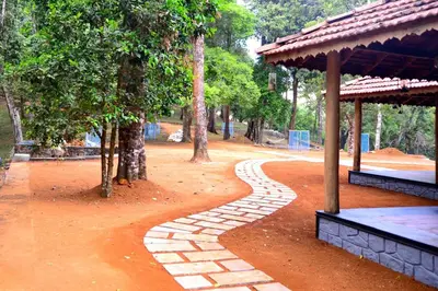 a walkway in a park with trees and a pavilion at 900 Woods Wayanad Eco Resort - A Sprawling Jungle Stay near Glass Bridge in Meppādi