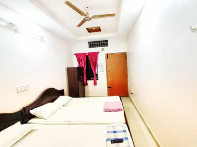 a bedroom with two beds and a ceiling fan at Sakthimurugan residency in Erode