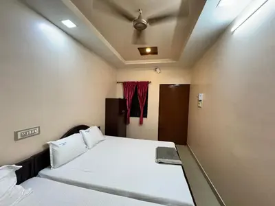 a bedroom with two beds and a window at Sakthimurugan residency in Erode