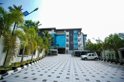 a car parked in front of a building with palm trees at Builda Park inn in Ottappālam