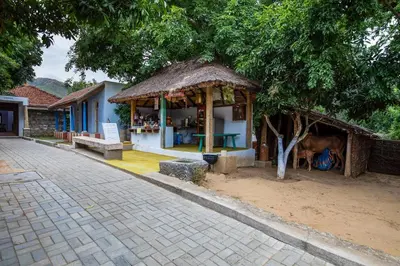 a small building with a cow standing in front of it at My Village - Eco Rural Resort in Coimbatore