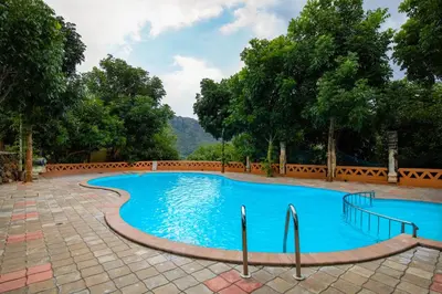 a large blue swimming pool with trees in the background at My Village - Eco Rural Resort in Coimbatore