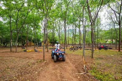 a man riding a quad bike in the woods at My Village - Eco Rural Resort in Coimbatore