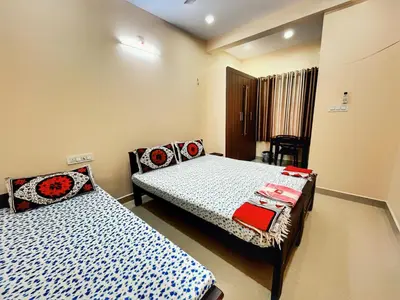 a bedroom with two beds and a chair in it at Thrissur Villas Home Stay in Trichūr