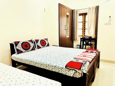 a bedroom with two beds and a chair in it at Thrissur Villas Home Stay in Trichūr