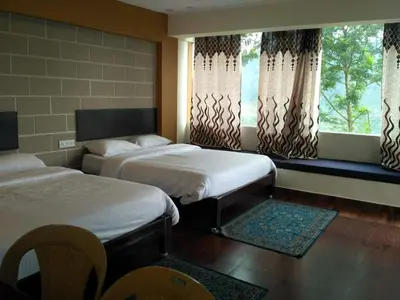 a hotel room with two beds and a window at The Meadows in Kodaikānāl