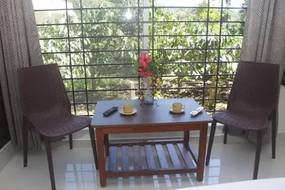 a table and two chairs in front of a window at Grand Misty Heaven in Madikeri
