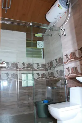 a bathroom with a shower with a toilet and a sink at KINGMAKER'S Plantation with River Stream in Madikeri