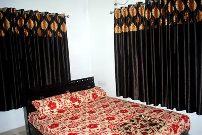 a bedroom with a bed and black curtains at NICE VILLA in Irimbranallūr
