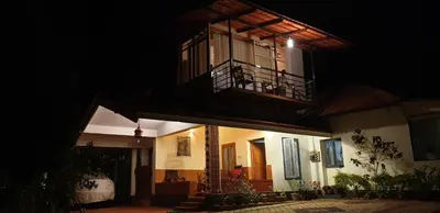 a house at night with a balcony and a patio at LAZY DAYS Wayanad in Cherambādi