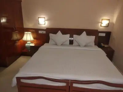 a bedroom with a large white bed with two lamps at KPM Regency in Palakkad