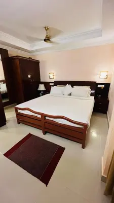 a bedroom with a large bed with white sheets and pillows at KPM Regency in Palakkad
