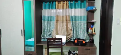 a desk with a chair in a room with a curtain at Garden House in Mysore