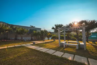 a bench in a park with palm trees and a building at Tuskers Hill by Poppys Anaikatti in Palghat