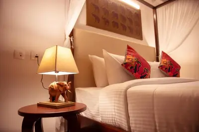 a bedroom with a bed and a lamp on a table at Tuskers Hill by Poppys Anaikatti in Palghat