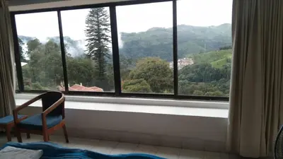 a chair sitting in front of a window with a view at Camellia Heights 1&2 in Coonoor