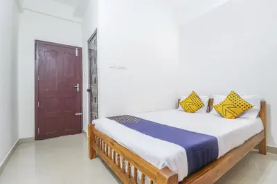 a bedroom with a bed with yellow and blue pillows at SPOT ON Rohini Inn Kadampuzha in Malappuram
