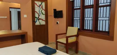 a room with a bed and a chair and a window at Gateway Airport Hotel in Kannur
