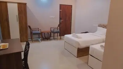a hotel room with a bed and a table and chairs at Gateway Airport Hotel in Kannur