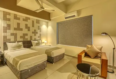 a bedroom with two beds and a couch and a window at AS AIRPORT Inn in Cochin