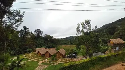 a view of a village with huts in a field at Ibni Springs in Madikeri