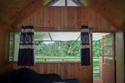 a room with a large window in a wooden house at Ibni Springs in Madikeri