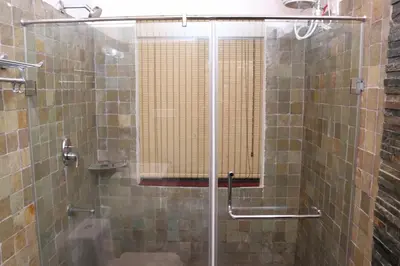 a shower with a glass door in a bathroom at Serene Woods in Madikeri